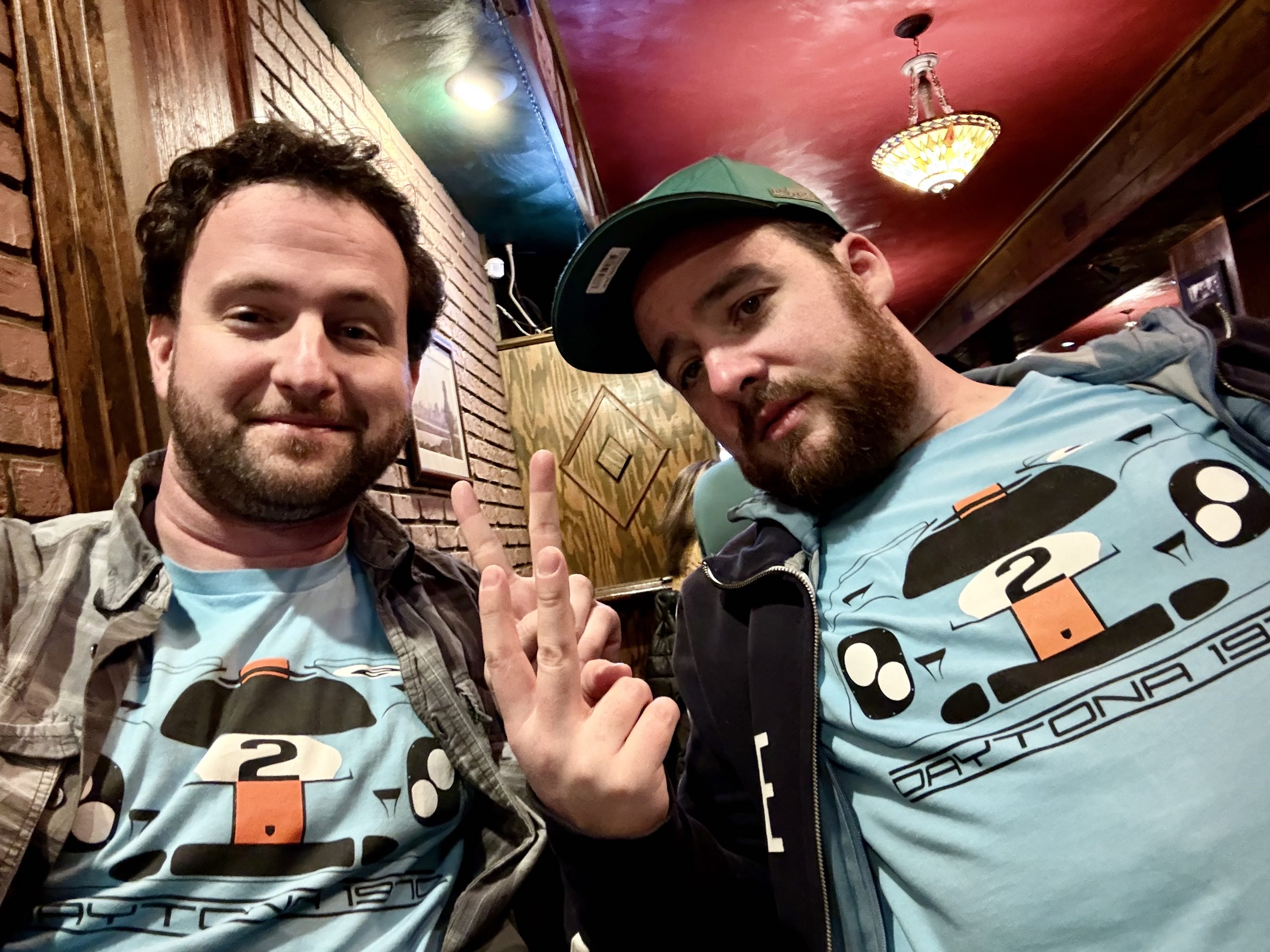 Two thirtysomething men with beards in jackets and identical race car tee shirts